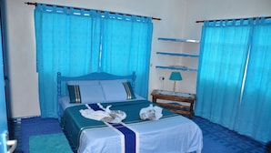 A room with a bed, a nightstand, a lamp, and a blue carpet. - Le Chateau Bleu (Mahé Island)