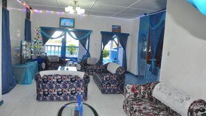 A living room with patterned sofas, a glass coffee table, and a Christmas tree. - Le Chateau Bleu (Mahé Island)