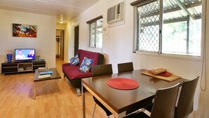 Una sala de estar con sofá, televisión, mesa de comedor y ventana con vistas.