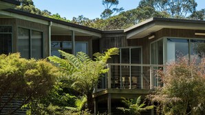 A modern house with large windows, a balcony, and a view of surrounding trees. - Gipsy Point Lodge (Gipsy Point)