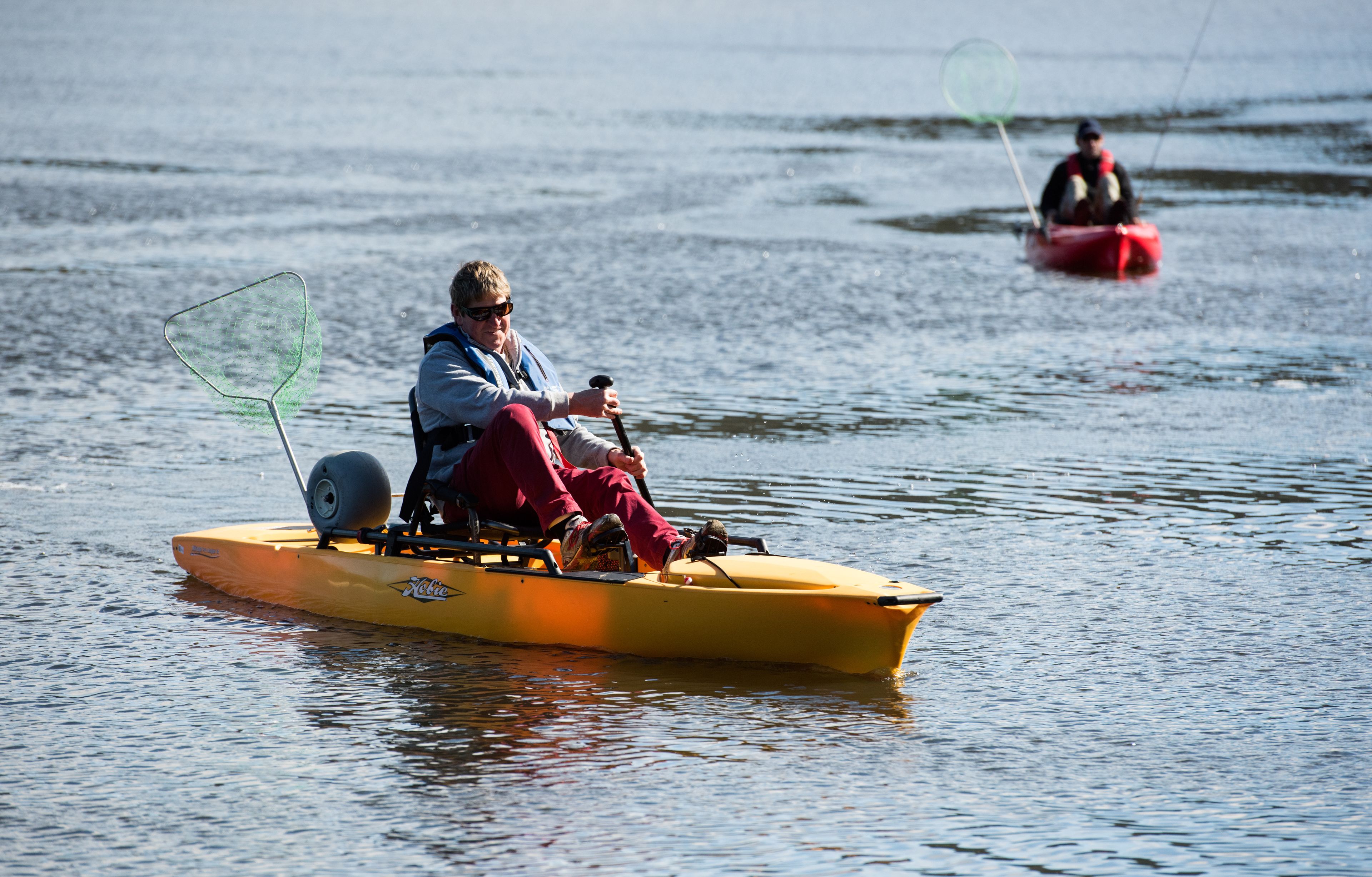 A person in a yellow kayak on calm water.