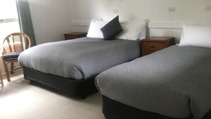 A hotel room with two beds, a wooden chair, and a small table.