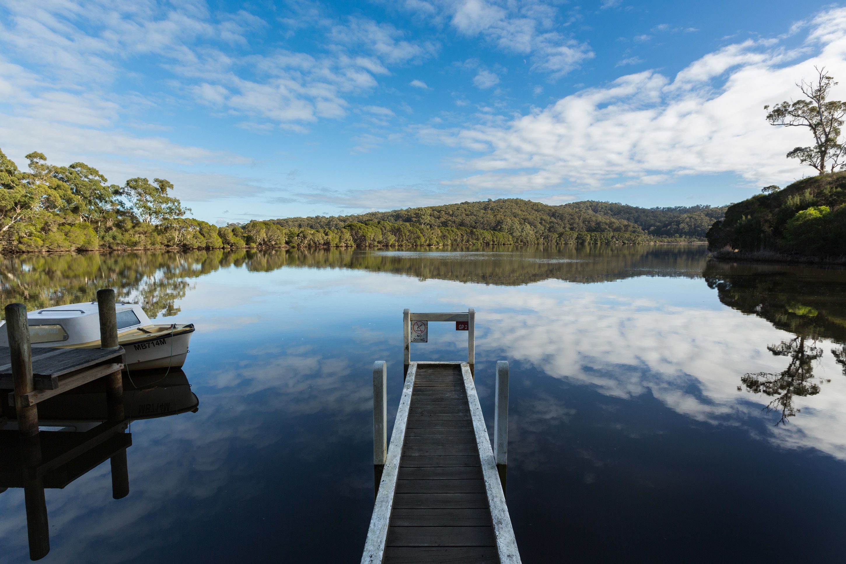 A dock extending into calm water with a boat moored at the end.