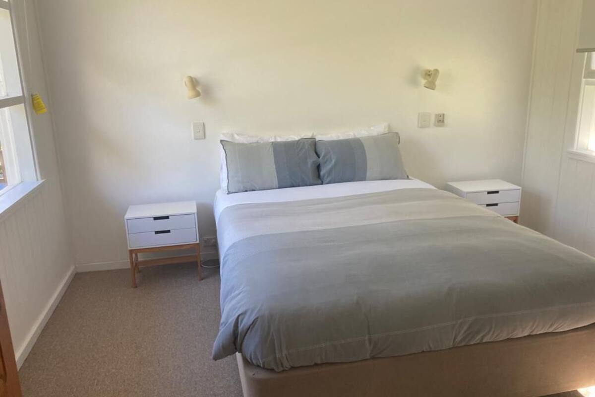 A bedroom with a bed, two bedside tables, and a window.