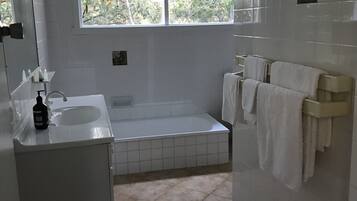 Un baño con bañera, lavabo, espejo y ventana.