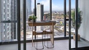 Een moderne kamer met een groot raam, een houten bureau, twee stoelen en een potplant.