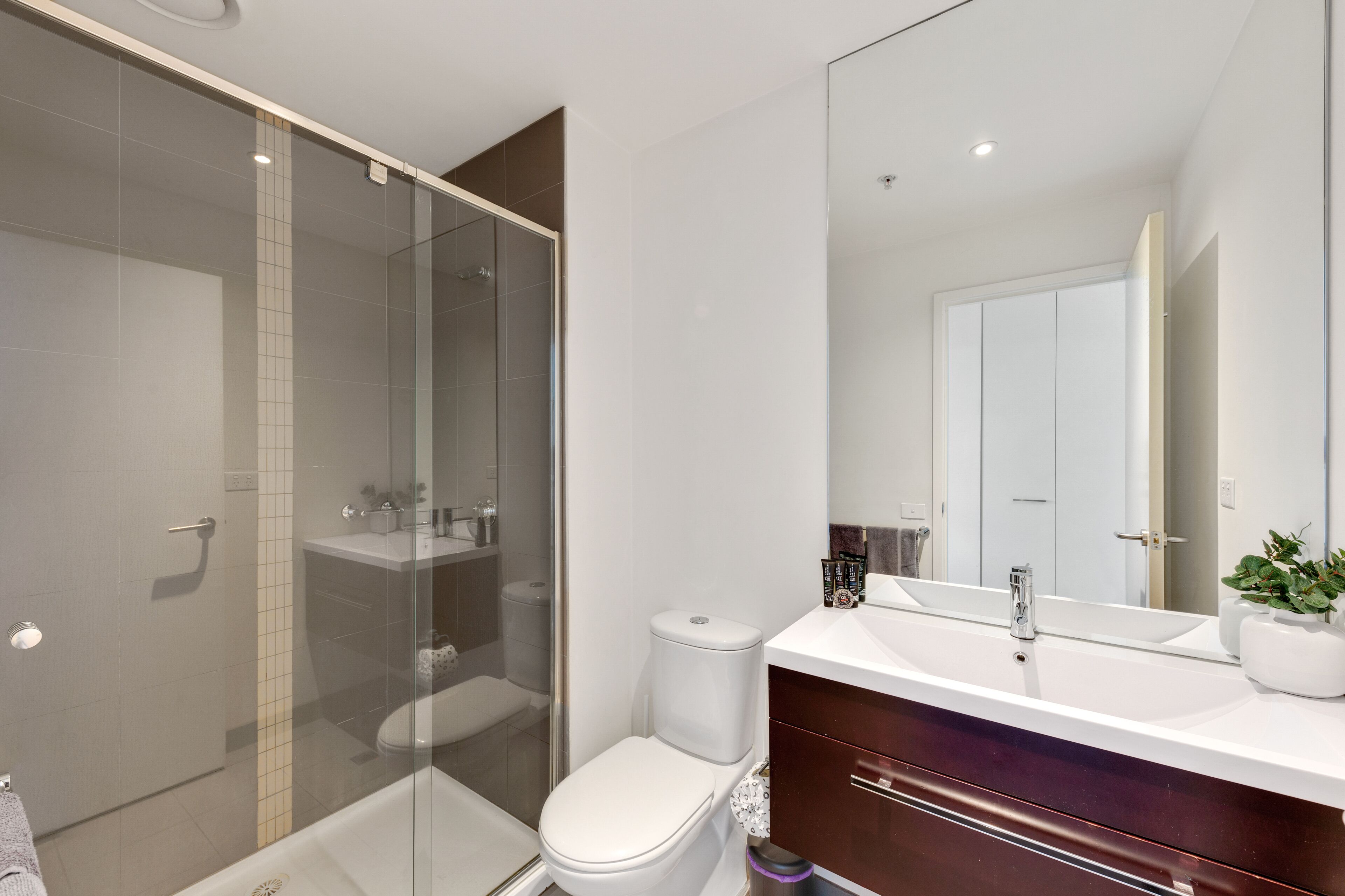 Un bagno moderno con doccia vetrata, un water bianco e un lavabo con specchio.