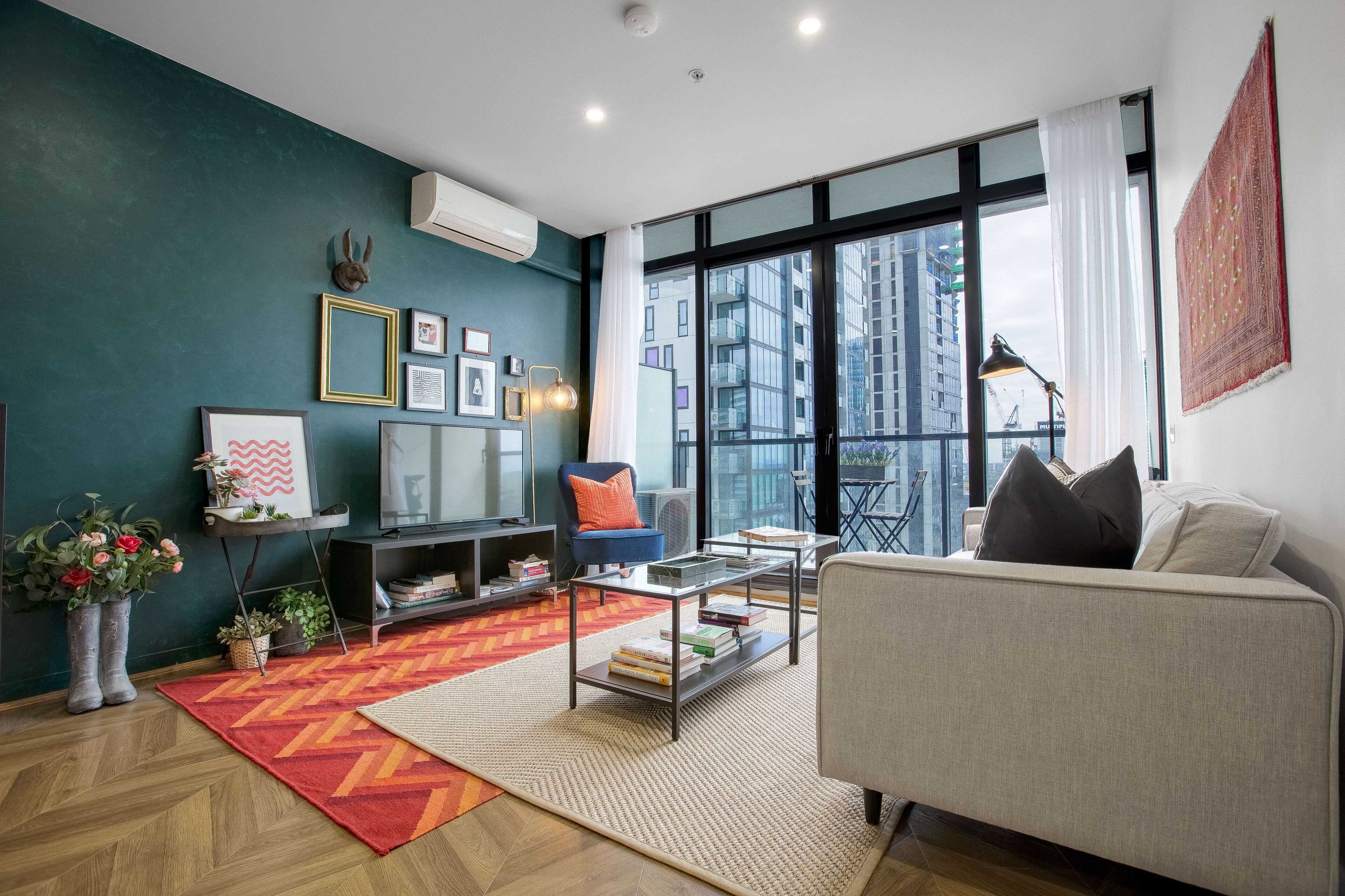 A modern living room with a sofa, coffee table, and a large window offering a city view.