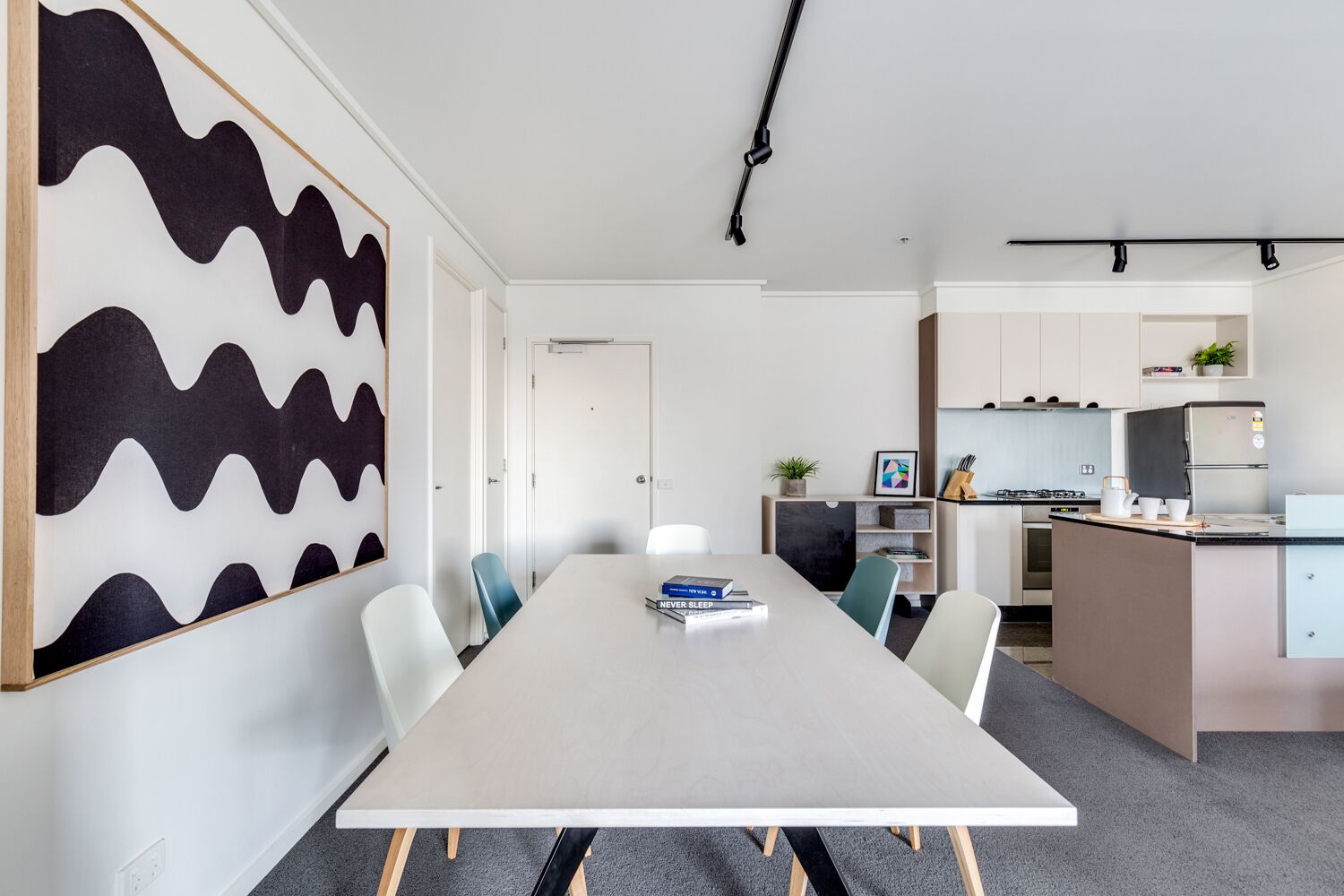 A modern kitchen with a built-in oven, a refrigerator, and a sink.