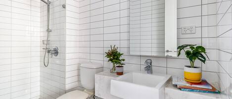 Een moderne badkamer met witte metro tegels, een witte wastafel, een spiegel en een douche.