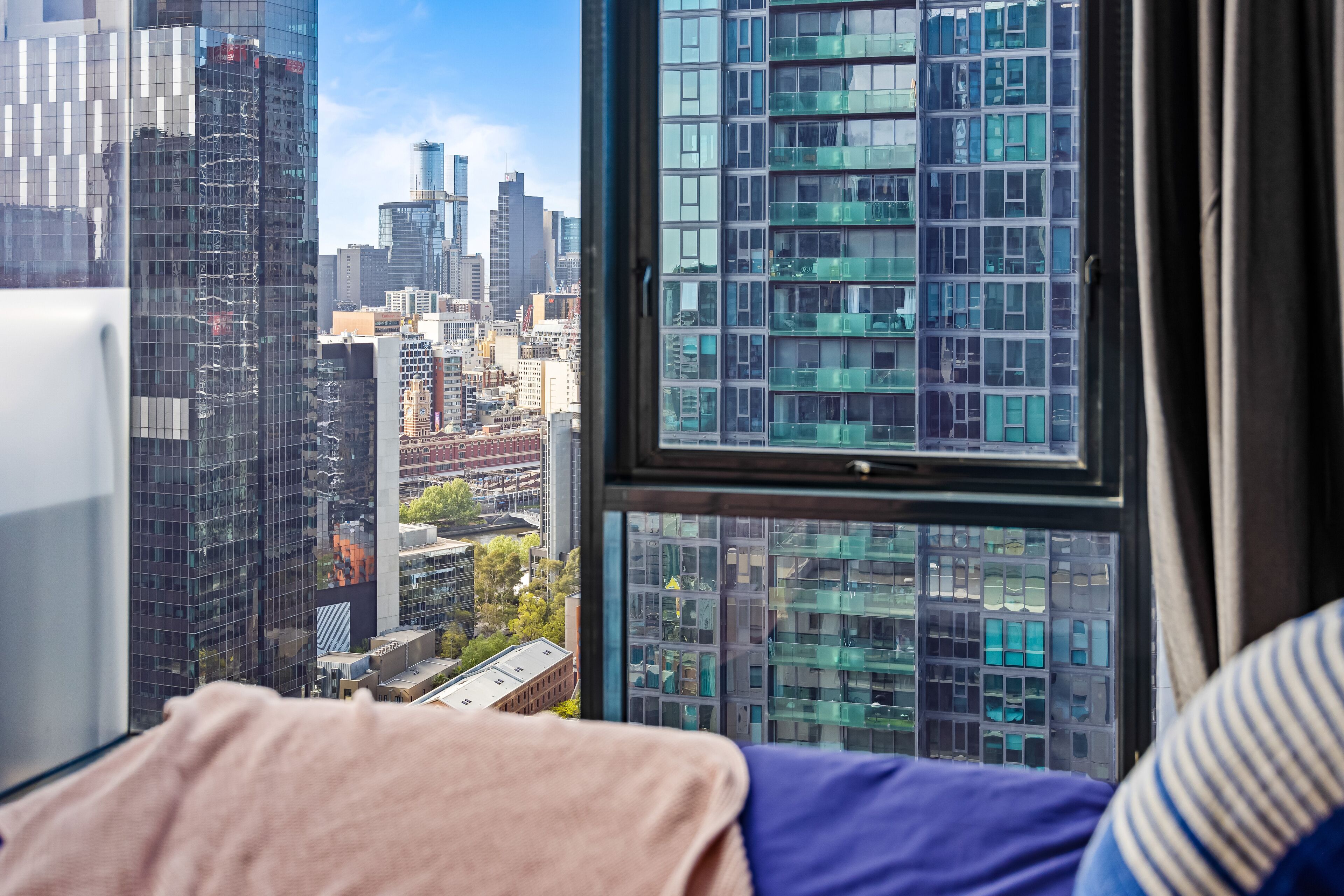 A bedroom with a large window overlooking a cityscape.