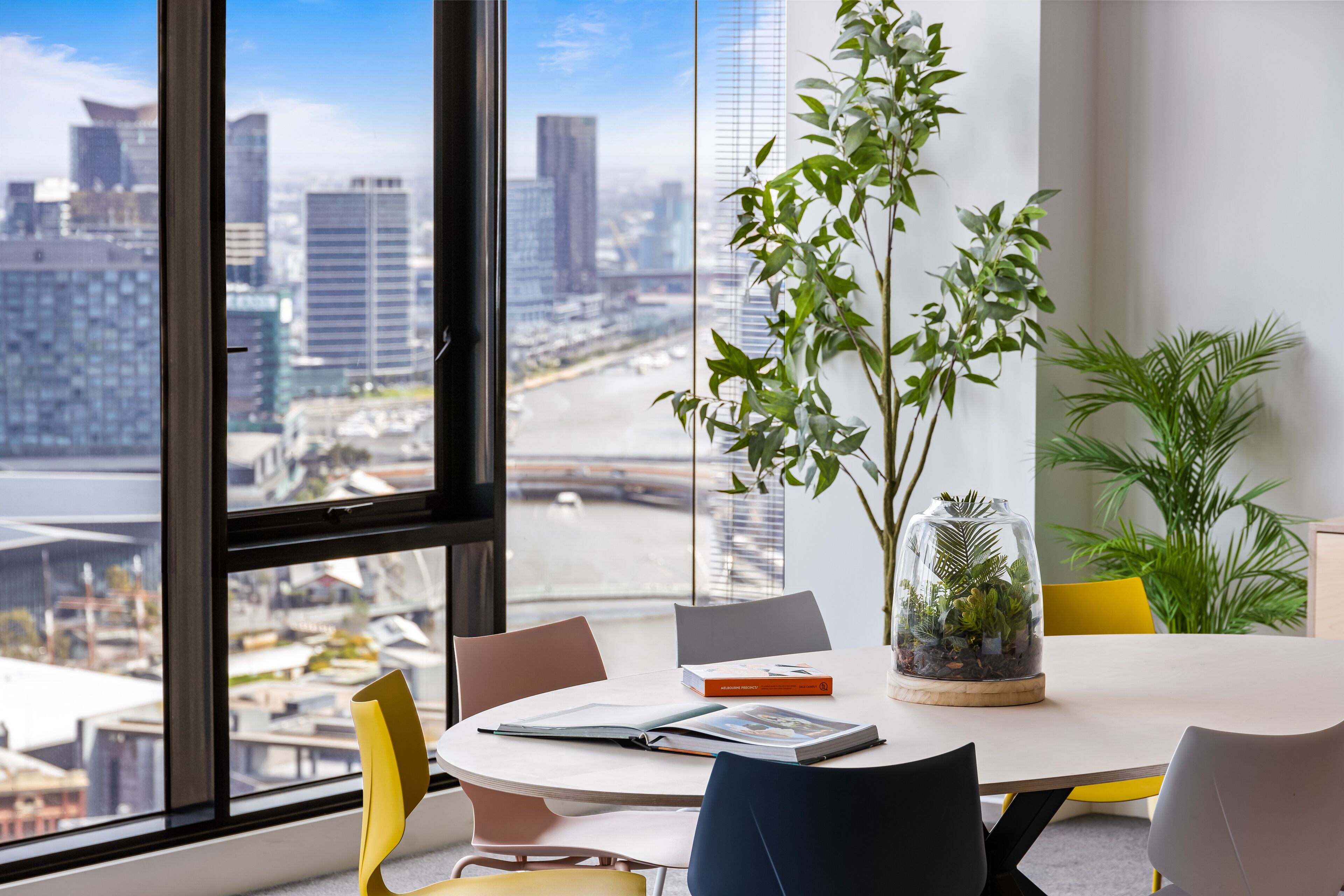 Un bureau moderne doté d’une grande fenêtre donnant sur un paysage urbain.