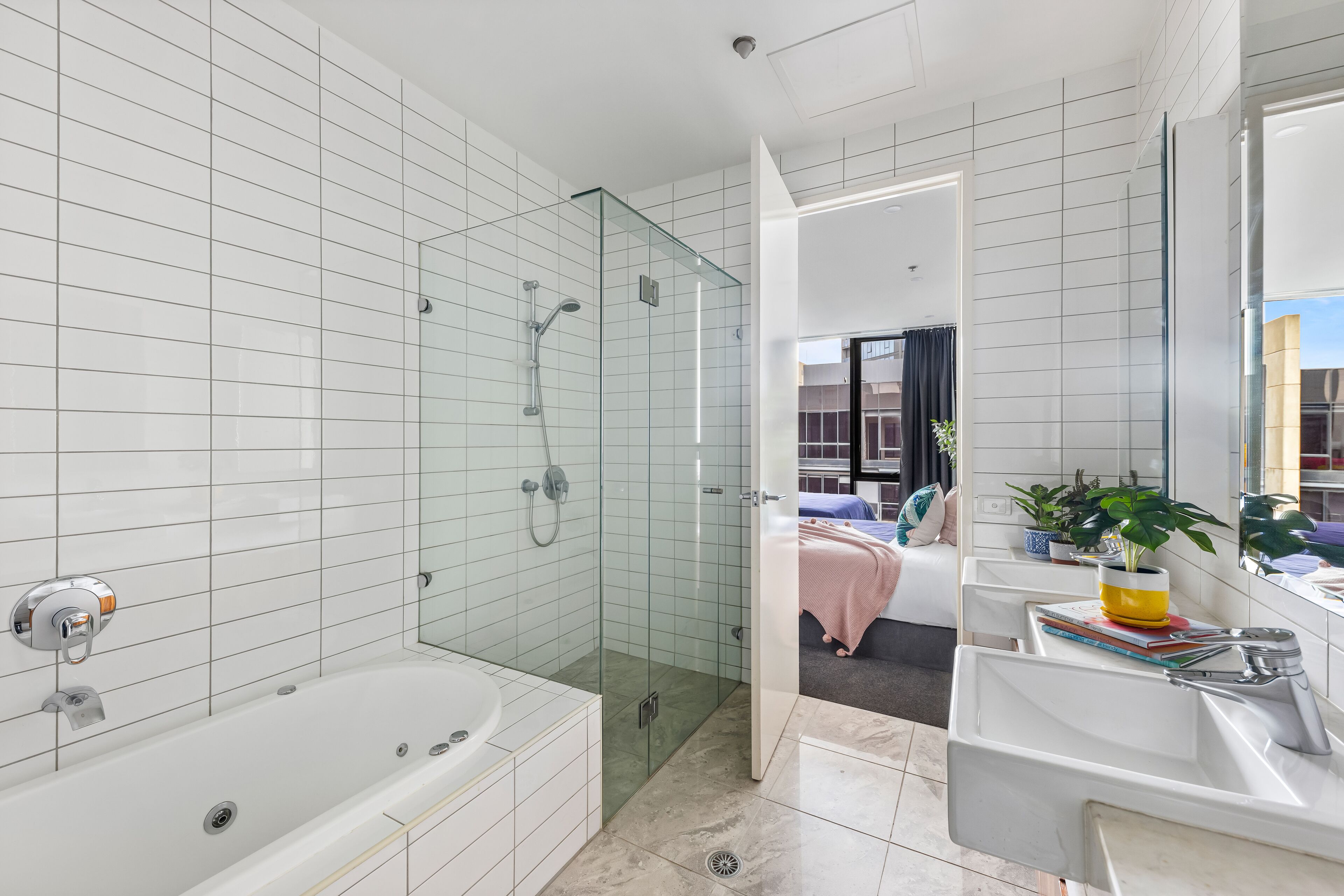 A modern bathroom with a glass-enclosed shower, a large bathtub, and a sink with a mirror.