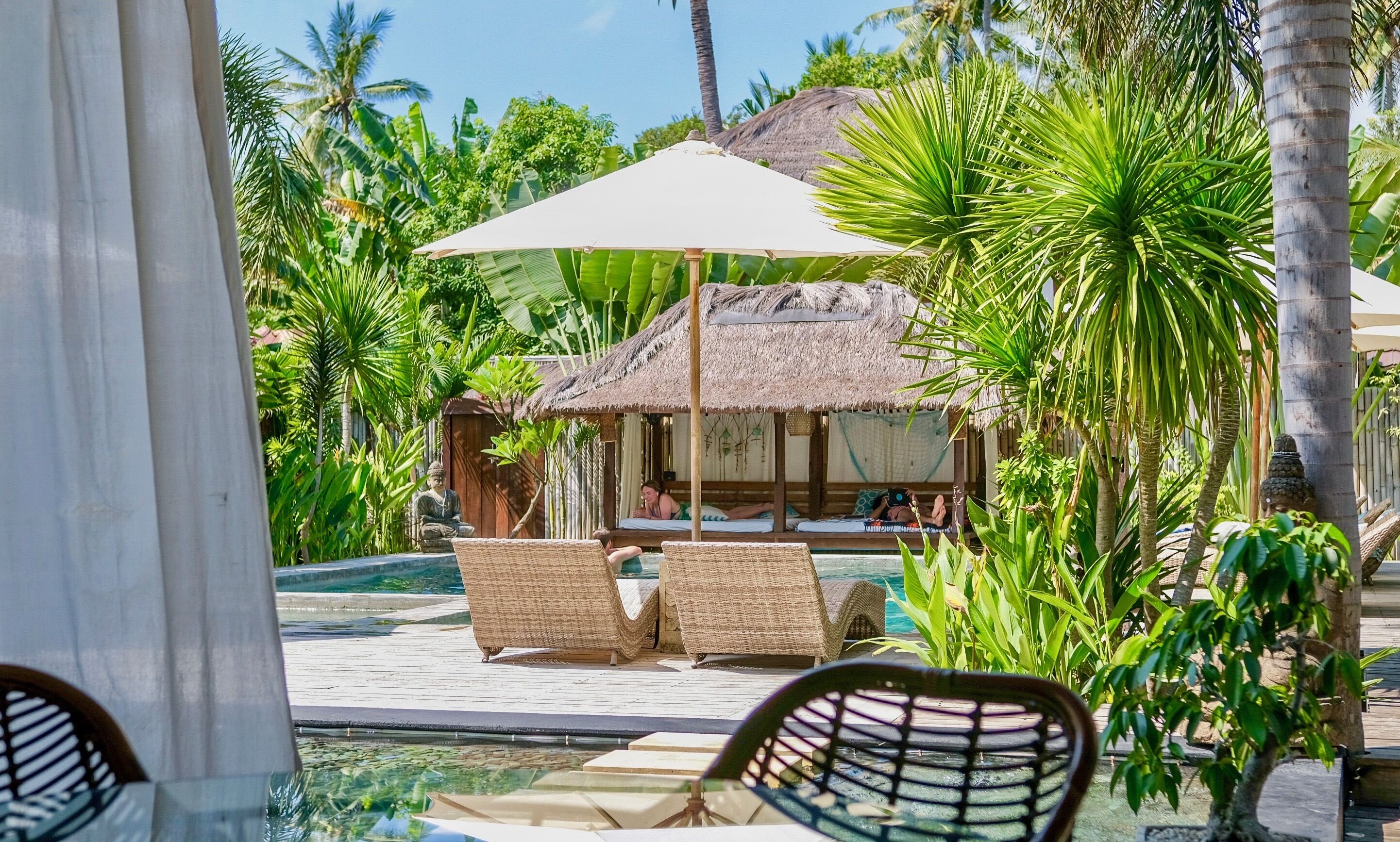 A poolside area with lounge chairs and a thatched-roof hut.