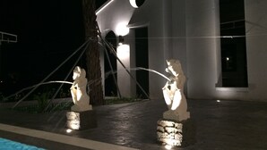 A nighttime view of a building with a circular skylight and two statues of animals. - True Love Villa (Hengchun)