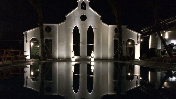 A large, illuminated building with a central arched entrance and two side wings, reflecting in a calm water body. - True Love Villa (Hengchun)
