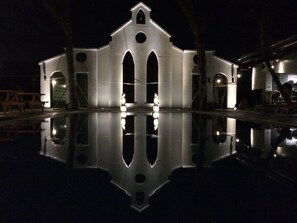 A large, illuminated building with a central arched entrance and two side wings, reflecting in a calm water body. - True Love Villa (Hengchun)