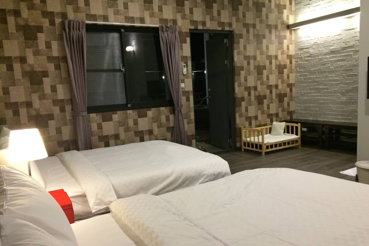 Una habitación de hotel con dos camas, un banco de madera y una ventana con cortinas.