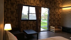 A room with a bed, a small table, a chair, and a window with curtains. - True Love Villa (Hengchun)