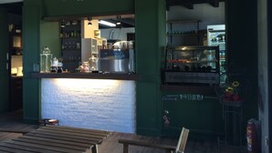 A restaurant interior with a brick wall, green columns, a counter with a menu sign, and a dessert display. - True Love Villa (Hengchun)