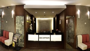 A reception area with a counter labeled "RECEPTION," a wall-mounted phone, and a "KEY DROP" sign. - RoomZ Hotel (Seria)