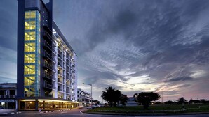 A modern hotel with a tall, rectangular structure, multiple floors, and a glass facade. - RoomZ Hotel (Seria)