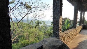 A stone structure with a view of a lush landscape and distant mountains. - Kurulu Estate (Rakwana)