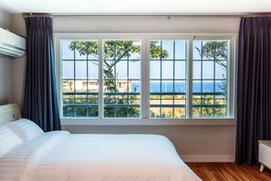 A hotel room with a large window, a bed, and an air conditioning unit.