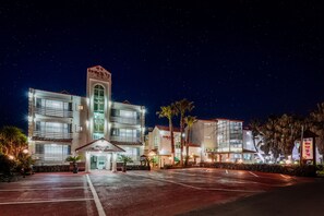 A multi-story hotel with a central tower, large windows, and a parking lot.