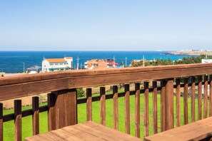A wooden deck with a view of the sea and buildings in the background.