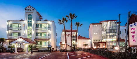 A hotel with multiple buildings, a parking lot, and palm trees.
