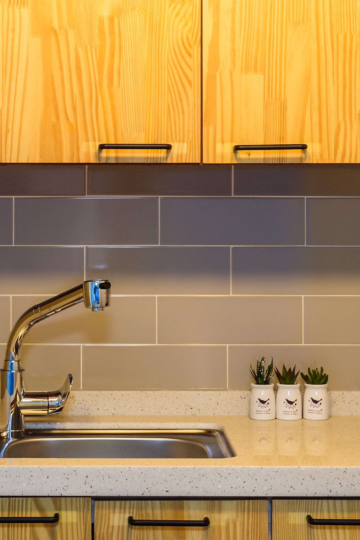 A kitchen with wooden cabinets, a stainless steel sink, and a tiled backsplash.