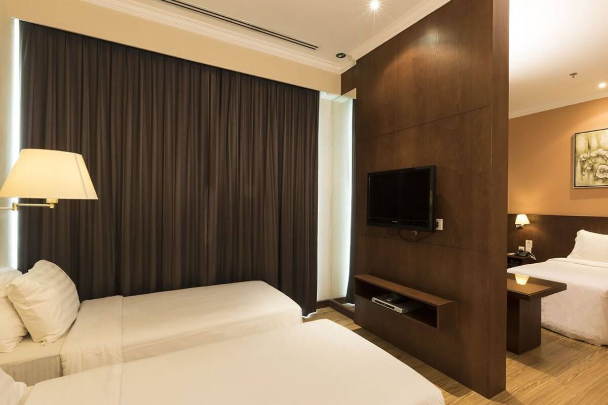 A hotel room with two beds, a TV, a desk, and a lamp.