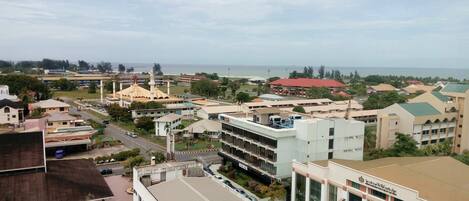 A cityscape with a prominent mosque, several commercial buildings, and a view of the sea.