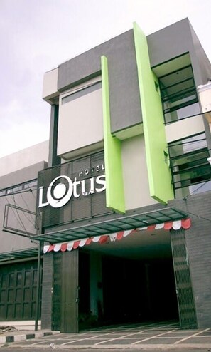 A modern hotel entrance with a prominent 'LOTUS' sign, a covered entrance area, and a gated driveway. - Hotel Lotus Subang (Subang)