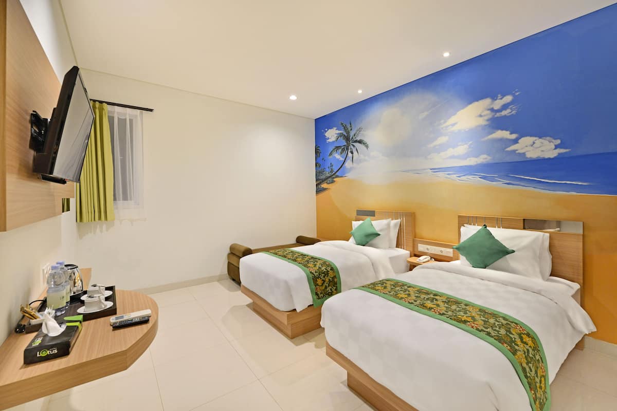 A hotel room with two beds, a TV, a desk with a remote control, and a mural of a beach scene.