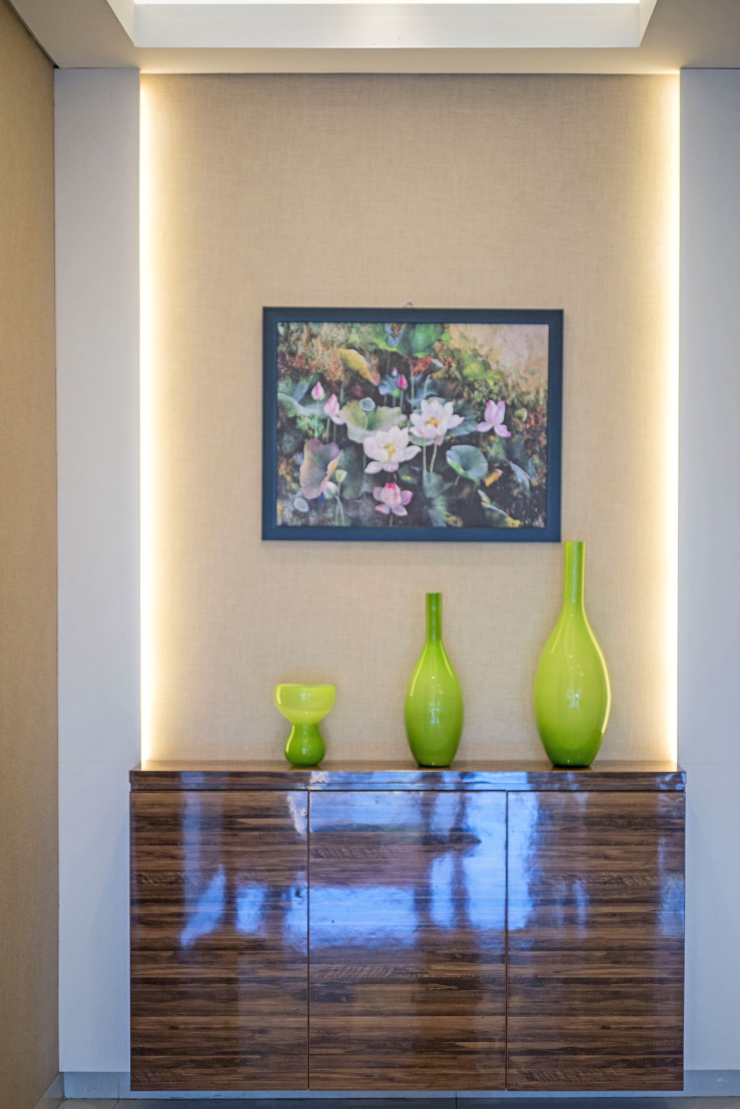 A wooden cabinet with two green vases and a small bowl on top.
