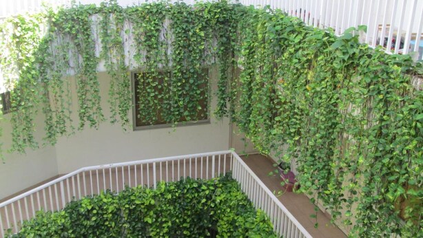 A multi-level atrium with a white railing, covered in lush green vines. - Legreen Suite Penjernihan (Jakarta)