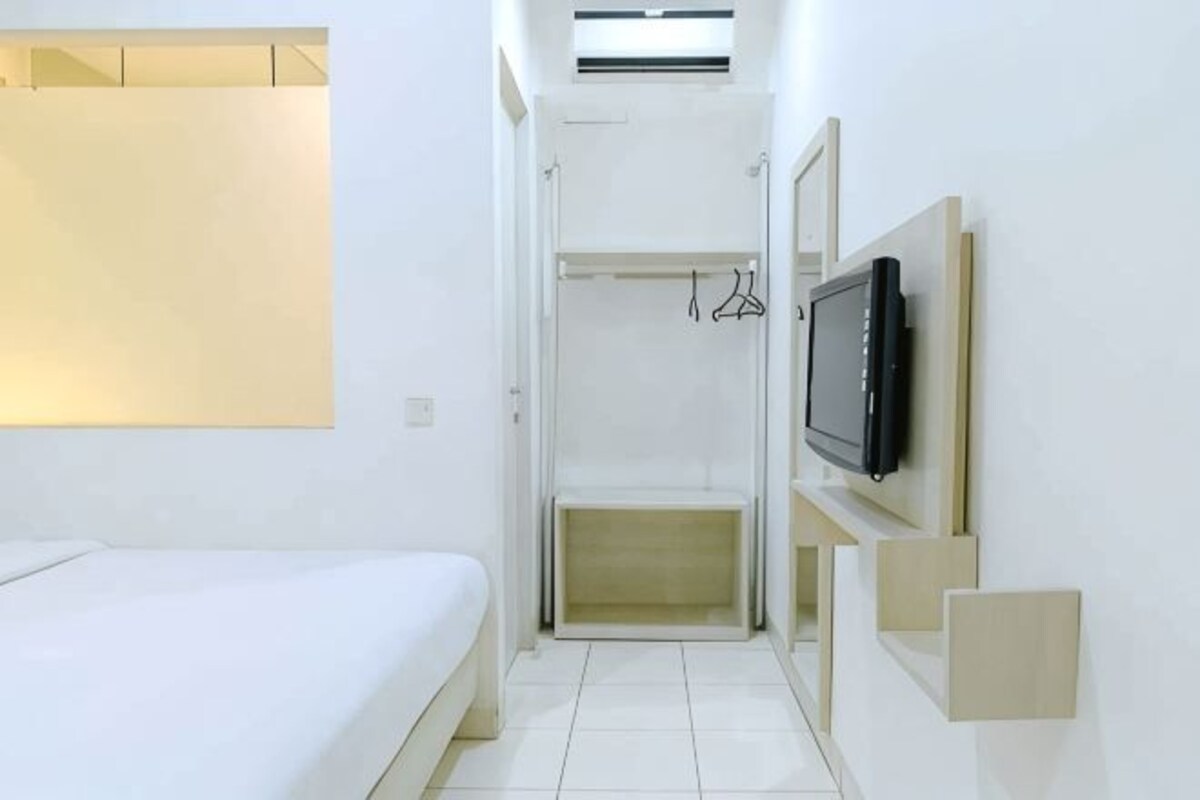 Een hotelkamer met een bed, een inloopkast, een televisie en een spiegel.
