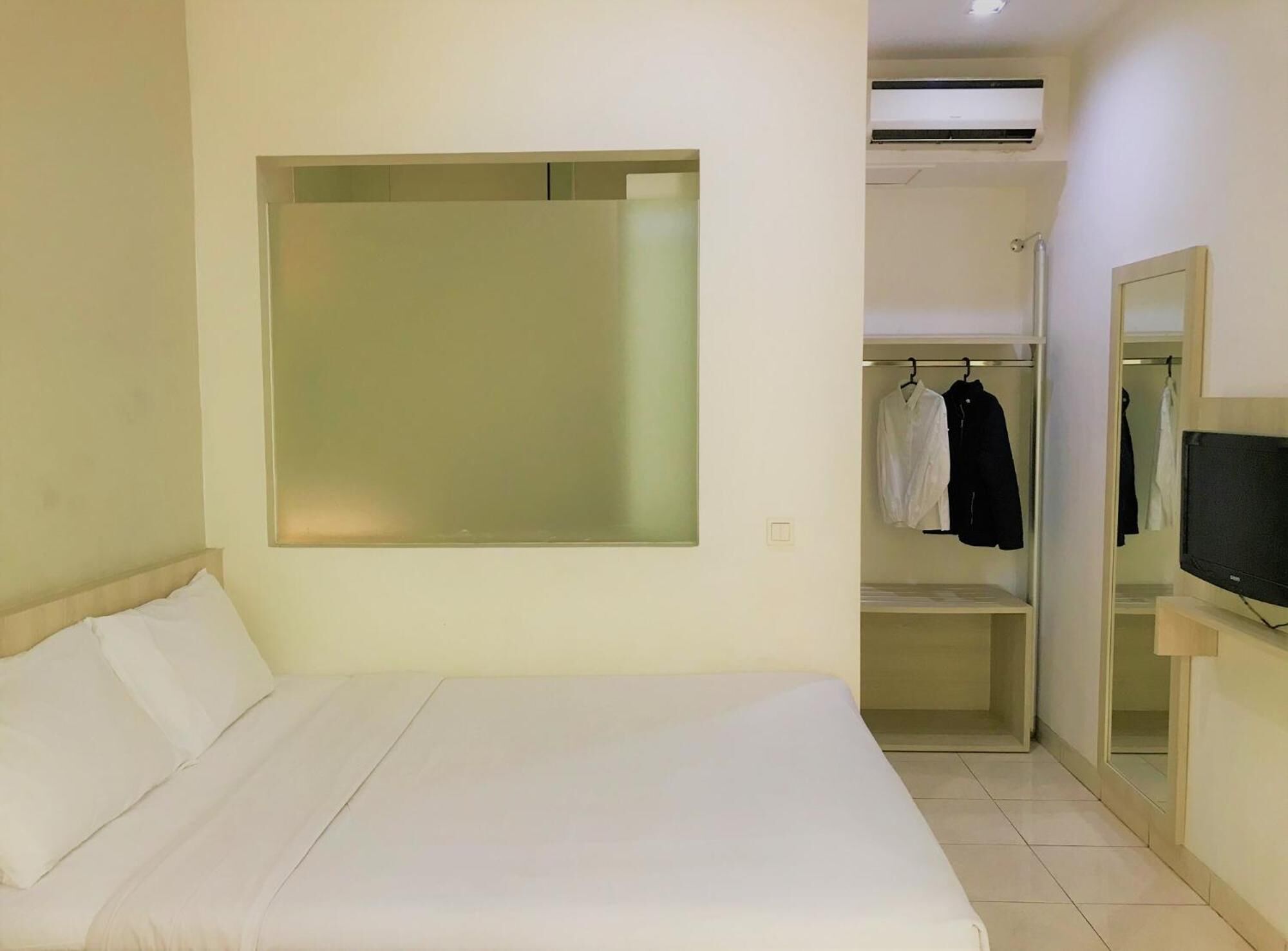 Una habitación de hotel con cama, armario y televisor.