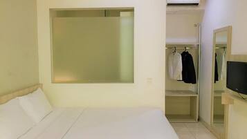 Una habitación de hotel con cama, armario y televisor.