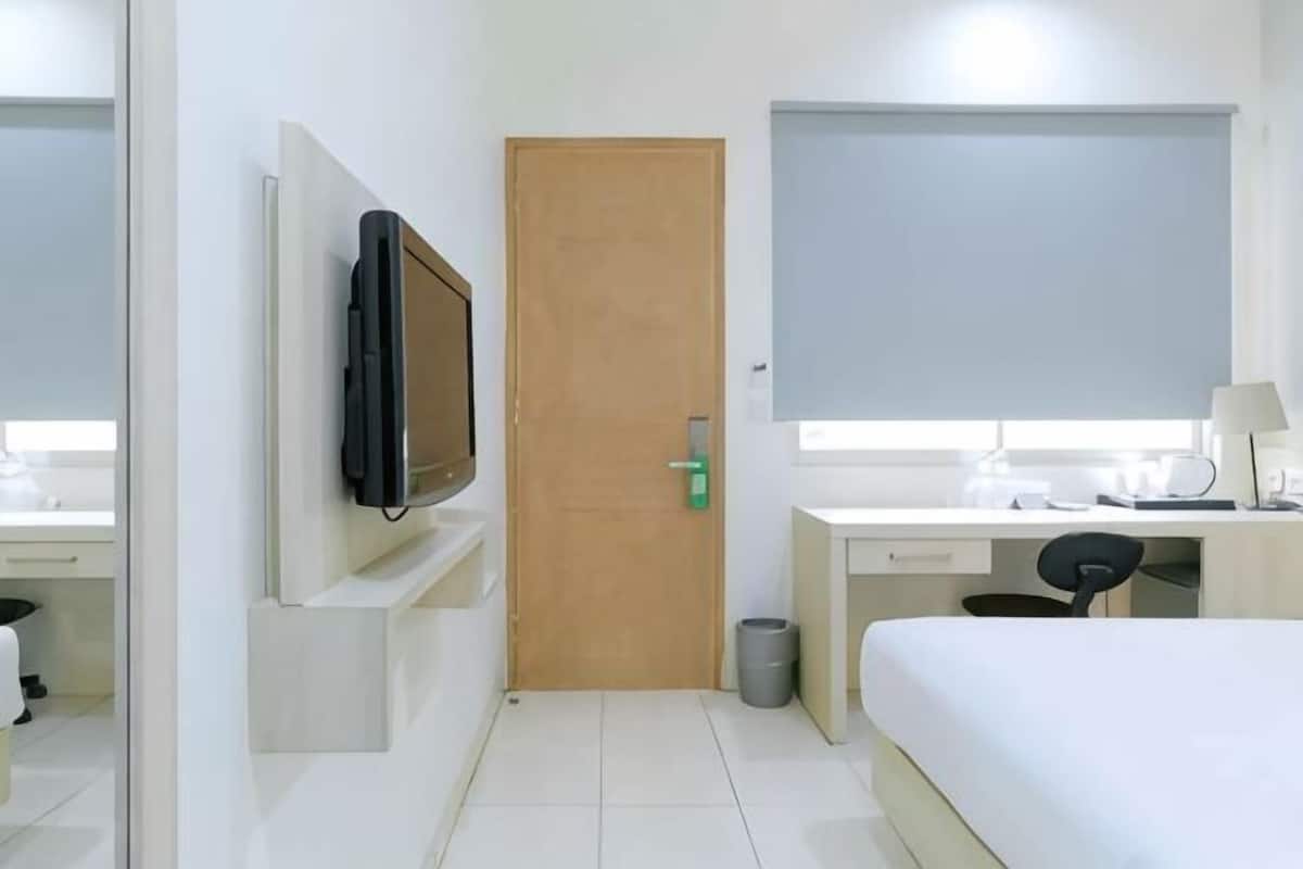Une chambre d’hôtel avec un lit, un bureau, une chaise, une télévision, une porte et une fenêtre.