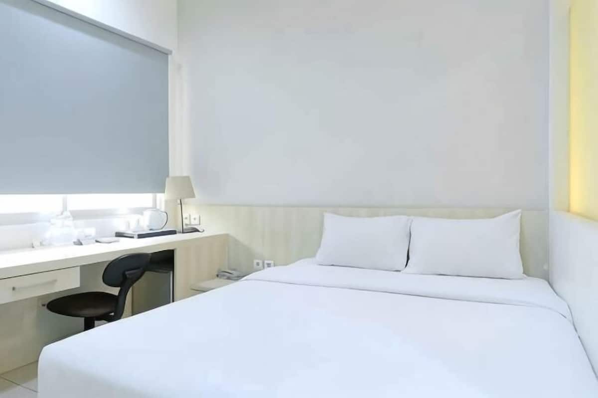 Une chambre d’hôtel avec un lit, un bureau, une chaise et une fenêtre.