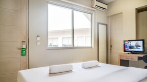A hotel room with a bed, a television, a desk, and a window. - Legreen Suite Penjernihan (Jakarta)