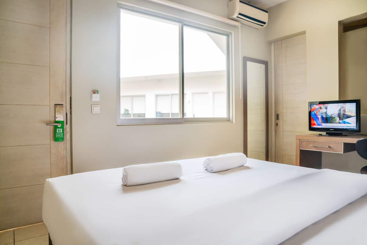 Une chambre d’hôtel avec un lit, une télévision, un bureau et une fenêtre.
