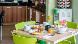 A dining table with plates of food, a bowl of yogurt, and a cup. - Legreen Suite Penjernihan (Jakarta)