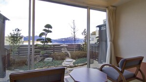 A room with a view of a garden, a wooden table, and two chairs. - Moriaki Ryokan (Shibukawa)