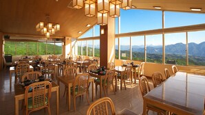 A spacious dining area with wooden furniture and large windows offering a view of the mountains. - Moriaki Ryokan (Shibukawa)
