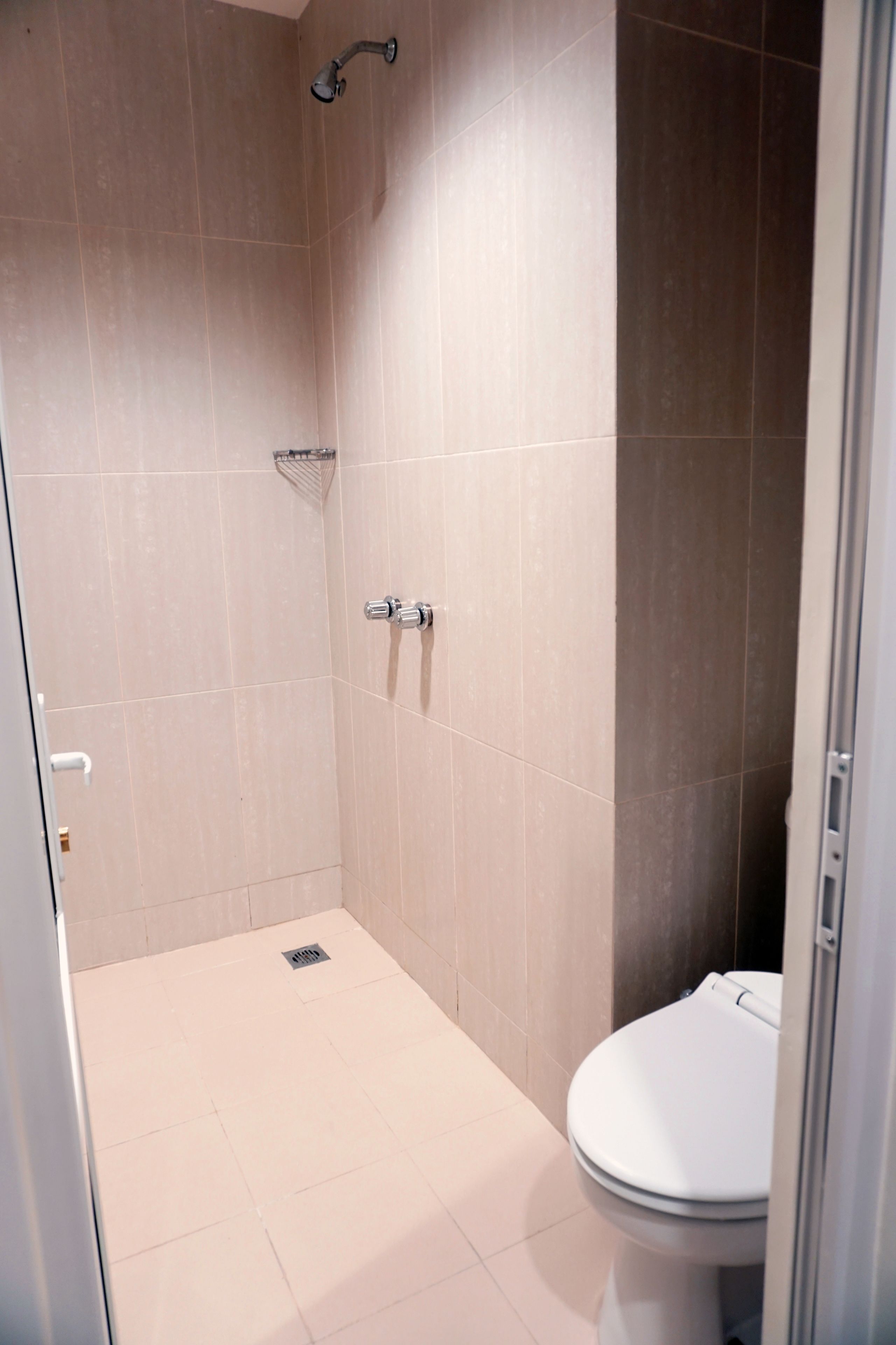 Un baño con ducha, inodoro y suelo de baldosas.