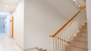 A staircase with wooden handrails and white balusters, leading to an upper floor. - LeGreen Suite Senayan (Jakarta)